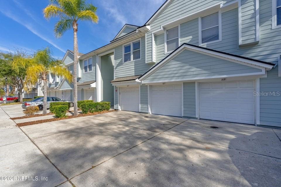 A row of light blue townhomes with white garage doors and palm trees in front — 7047 DEER LODGE CIRCLE UNIT 108, JACKSONVILLE, FL