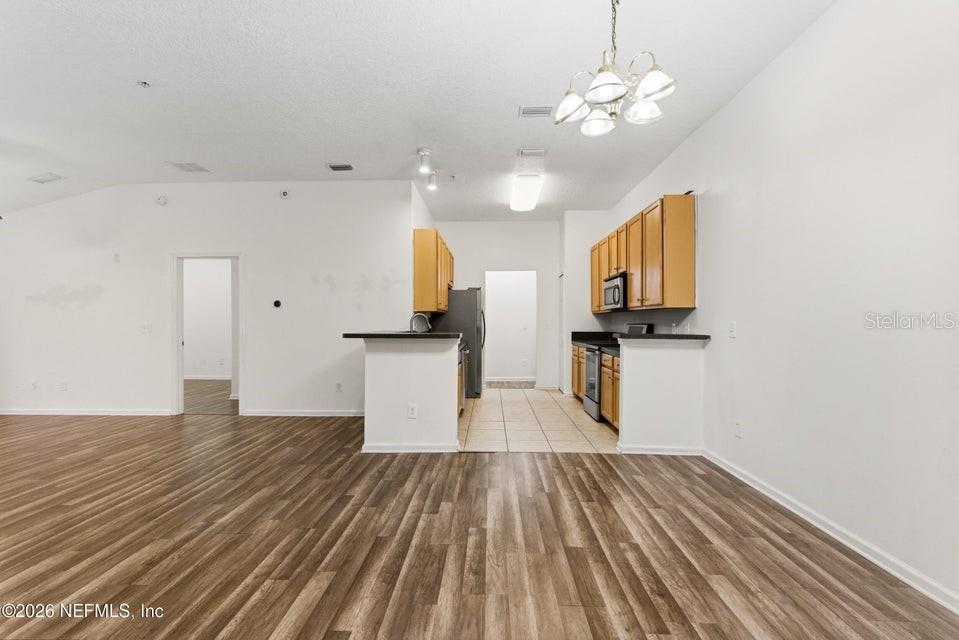 This kitchen features wood cabinets, dark countertops, and tile flooring, opening into a living area — 7047 DEER LODGE CIRCLE UNIT 108, JACKSONVILLE, FL