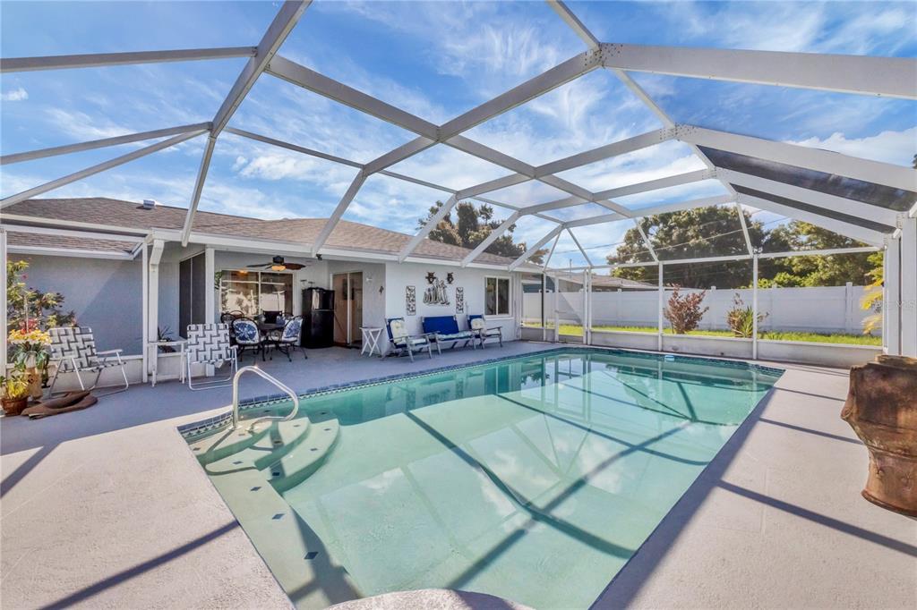 A screened-in patio features a rectangular swimming pool with built-in steps and outdoor furniture — 2339 LAKE VIEW BOULEVARD, PORT CHARLOTTE, FL