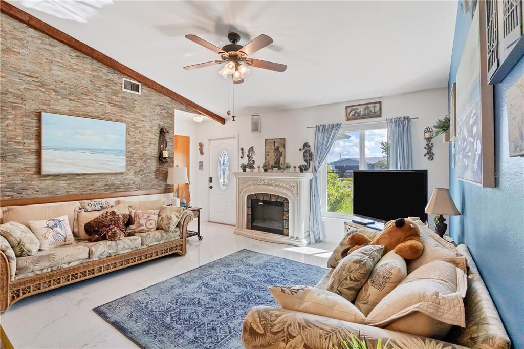 A living room features a stone accent wall, a fireplace, and a blue area rug — 2339 LAKE VIEW BOULEVARD, PORT CHARLOTTE, FL