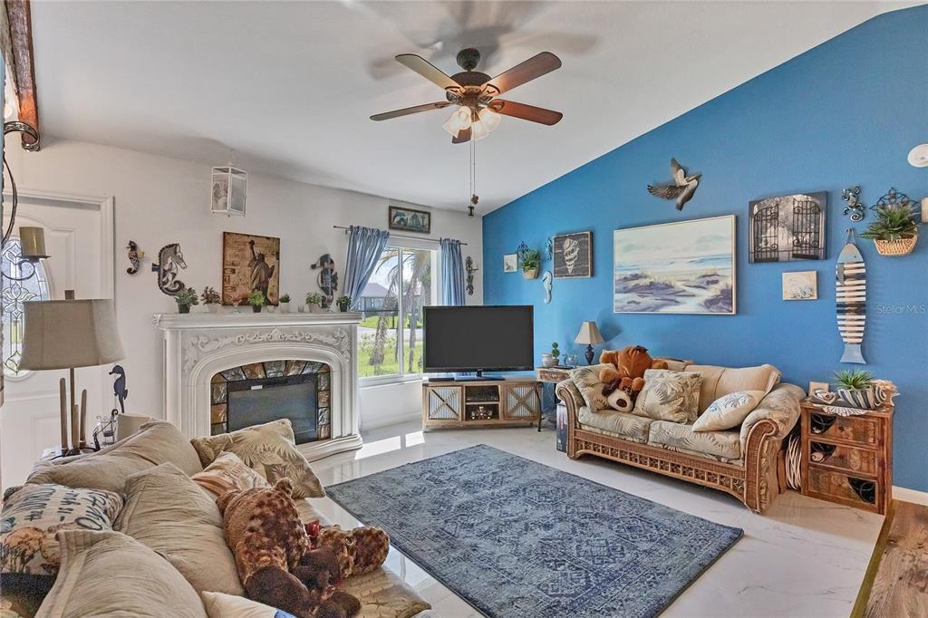 A living room features a fireplace, a blue accent wall, and a ceiling fan — 2339 LAKE VIEW BOULEVARD, PORT CHARLOTTE, FL
