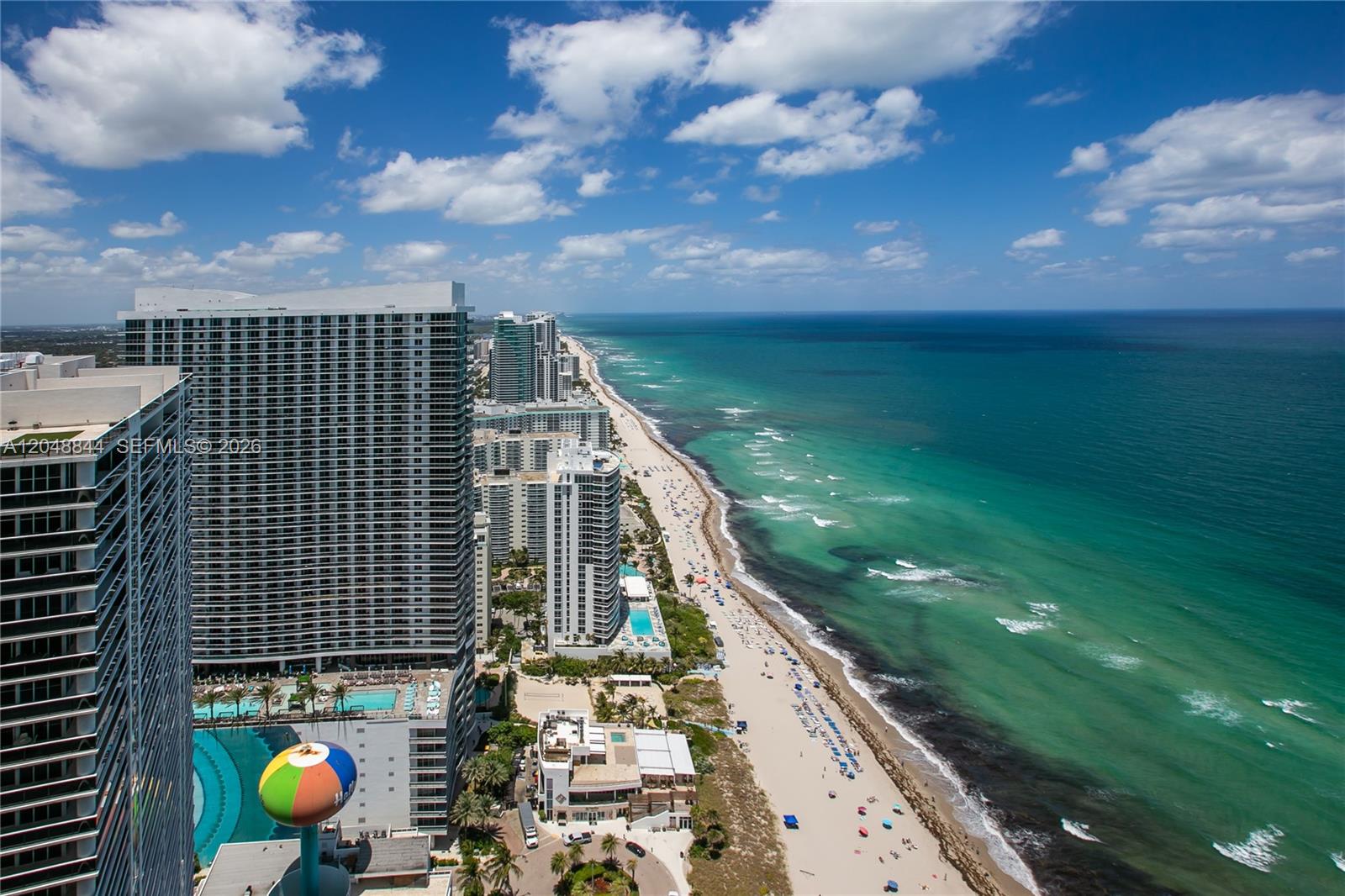 An aerial view shows high-rise buildings along a sandy beach and the turquoise ocean — 1830 S Ocean Dr # 4812, Hallandale Beach FL 33009, HALLANDALE BEACH, FL