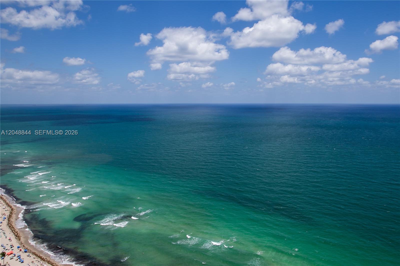 An aerial view shows a sandy beach meeting the turquoise and deep blue ocean — 1830 S Ocean Dr # 4812, Hallandale Beach FL 33009, HALLANDALE BEACH, FL