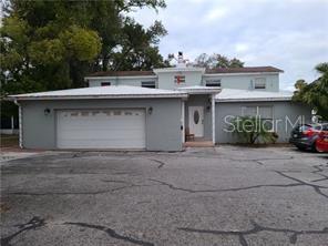 A two-story house with a light gray exterior, a white garage door, and a paved driveway — 205 W AMELIA AVENUE UNIT A, TAMPA, FL