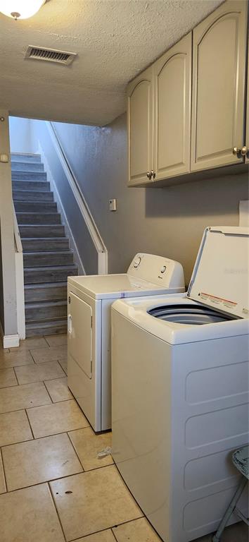 A laundry room with a washer and dryer, tile flooring, and stairs leading upward — 205 W AMELIA AVENUE UNIT A, TAMPA, FL