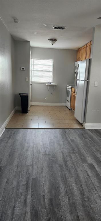 A kitchen with light tile flooring, white appliances, and wood cabinets transitions to gray wood flooring — 205 W AMELIA AVENUE UNIT A, TAMPA, FL