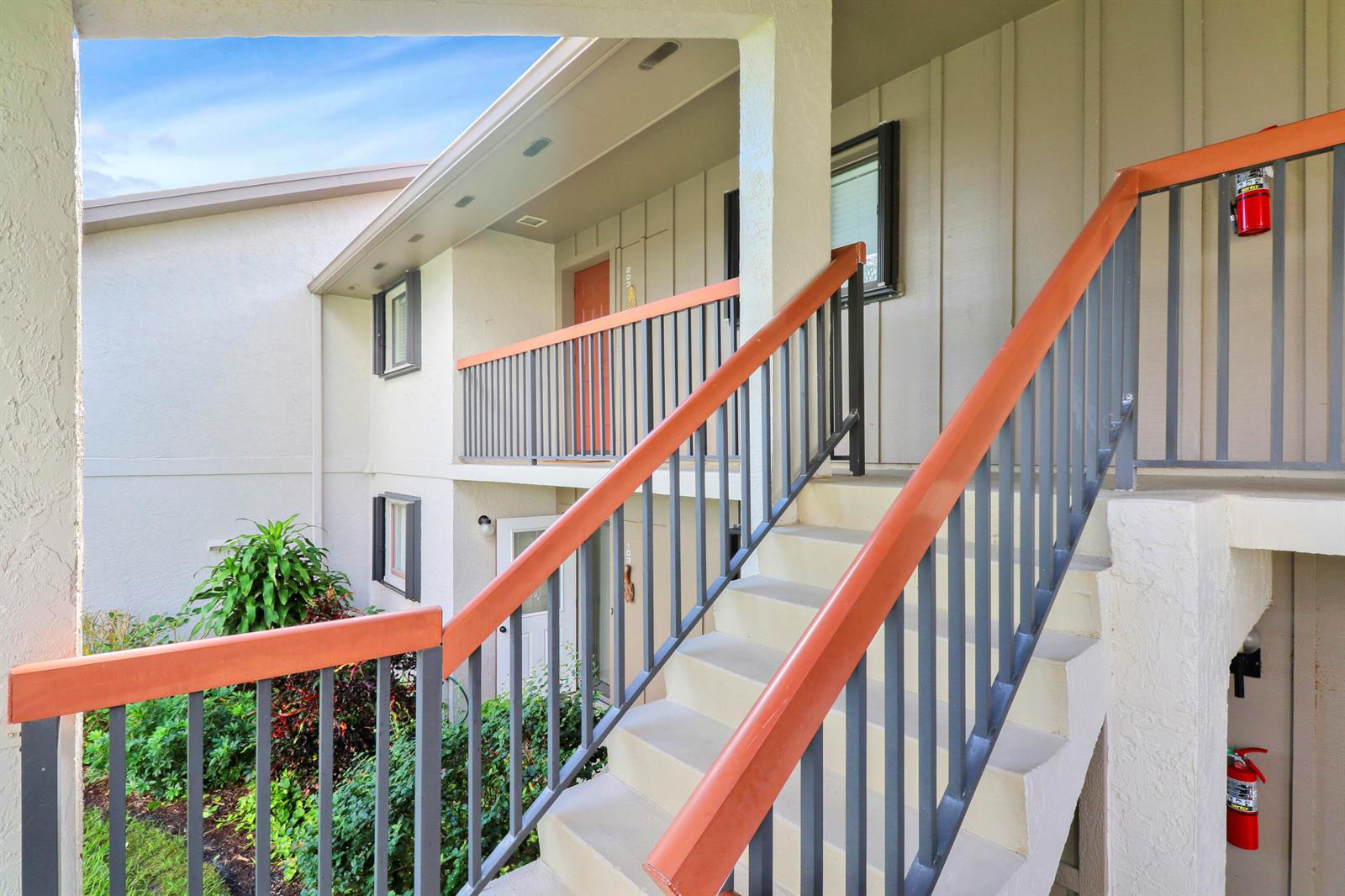 An exterior view of a two-story apartment building with concrete stairs and metal railings — 1600 NE Dixie Highway # 203, Jensen Beach FL 34957, JENSEN BEACH, FL