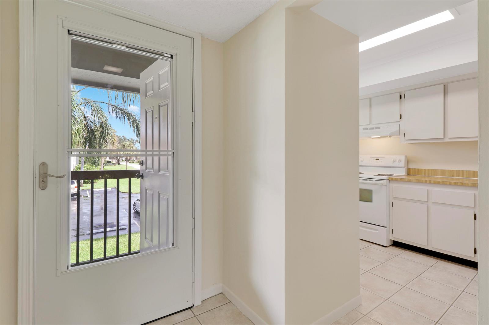 A view from a tiled entryway looking toward a kitchen with white cabinets and appliances — 1600 NE Dixie Highway # 203, Jensen Beach FL 34957, JENSEN BEACH, FL