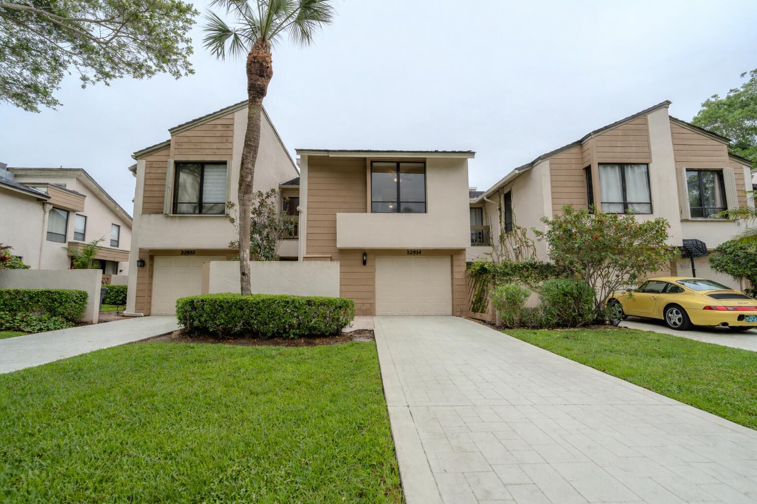 A living room with a sectional sofa, wood-paneled wall, television, and an open-concept kitchen — 22954 Ironwedge Drive, Boca Raton FL 33433, BOCA RATON, FL