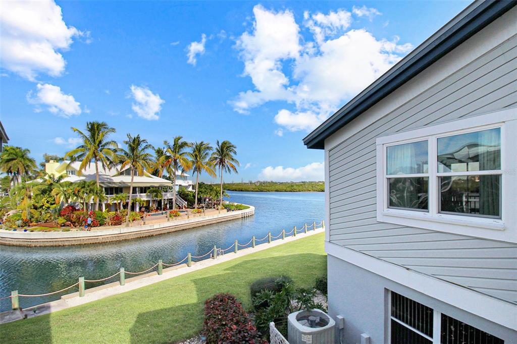 An exterior view of a house overlooking a canal with palm trees and a lawn — 1373 SIESTA BAYSIDE DRIVE UNIT 1373-C, SARASOTA, FL