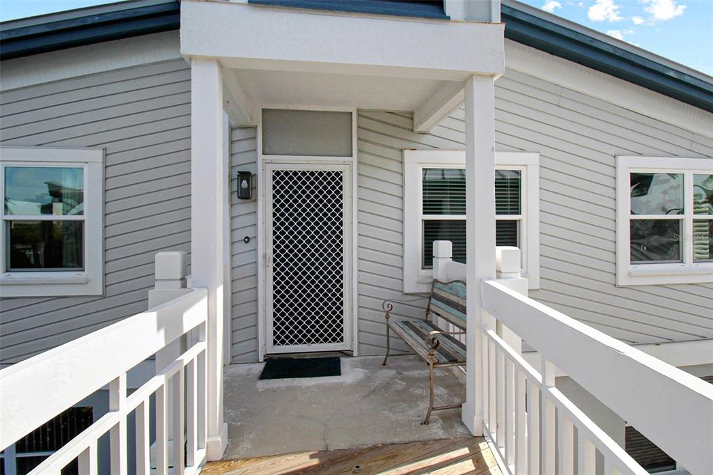 An elevated wooden deck leads to a front door with a white security screen — 1373 SIESTA BAYSIDE DRIVE UNIT 1373-C, SARASOTA, FL