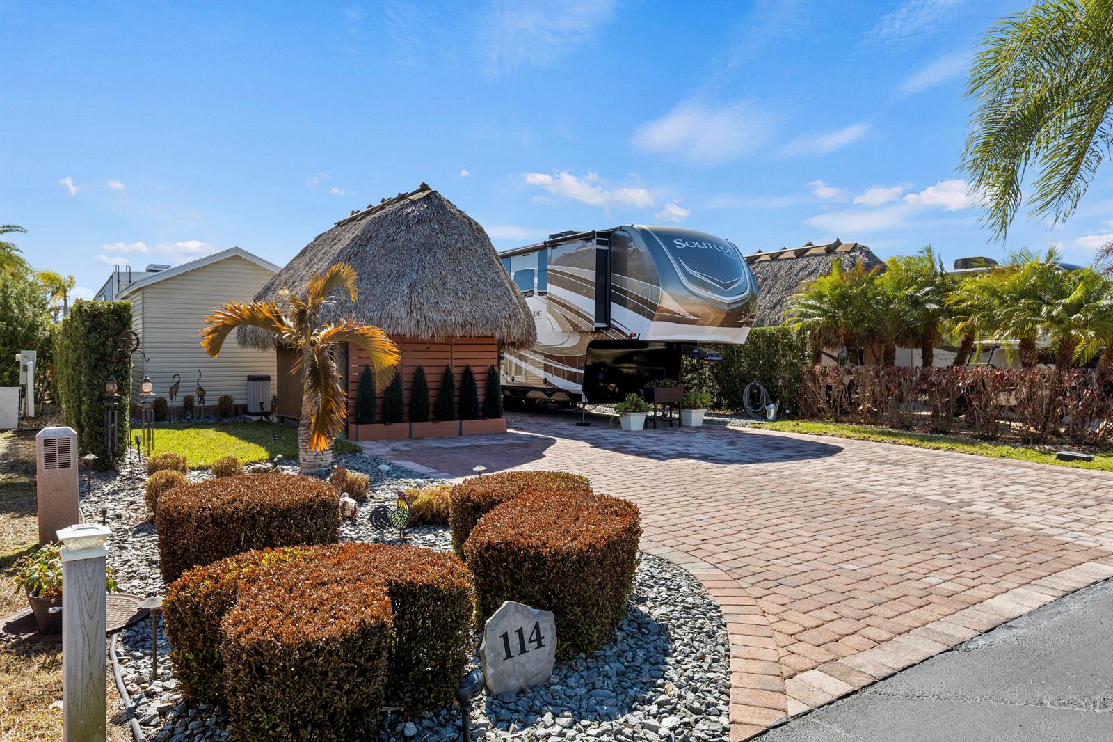 A paved driveway leads to a thatched-roof tiki hut and a parked fifth-wheel RV — 532 SW 38th Trace, Okeechobee FL 34974, OKEECHOBEE, FL
