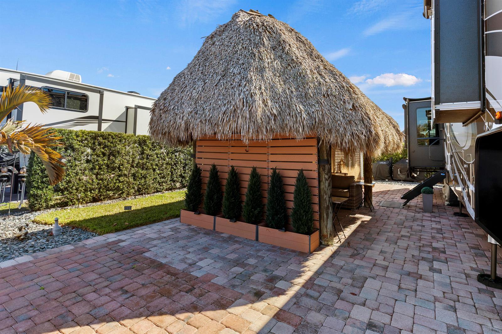 A thatched-roof tiki hut sits on a brick patio between two parked recreational vehicles — 532 SW 38th Trace, Okeechobee FL 34974, OKEECHOBEE, FL