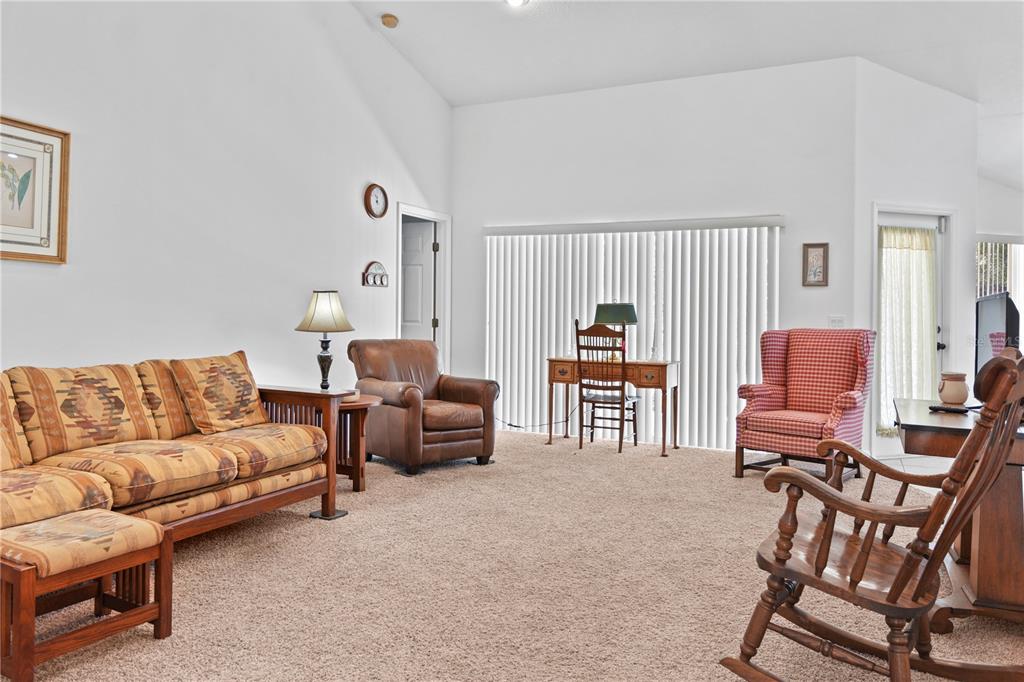 A living room features a patterned sofa, leather armchair, wooden rocking chair, and a desk — 800 VIRGINIS, CITRUS SPRINGS, FL