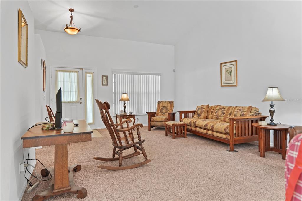 A living room features beige carpeting, a wooden rocking chair, a patterned sofa, and vaulted ceilings — 800 VIRGINIS, CITRUS SPRINGS, FL