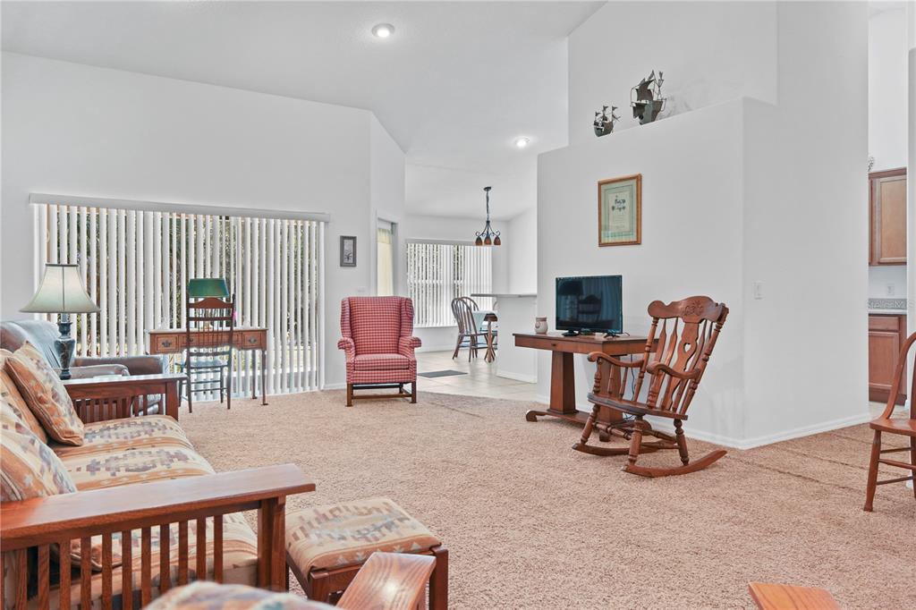 A living room with beige carpet, a red plaid armchair, and a wooden rocking chair — 800 VIRGINIS, CITRUS SPRINGS, FL