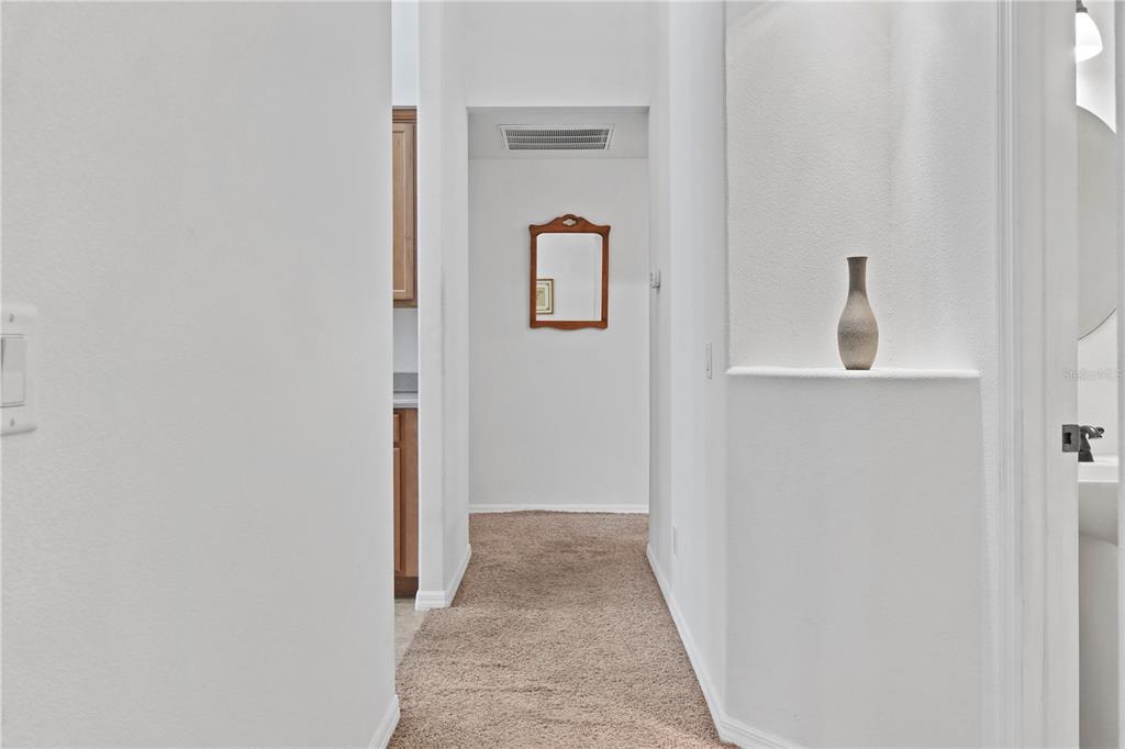 A carpeted hallway leads to a doorway, featuring a wall niche with a decorative vase — 800 VIRGINIS, CITRUS SPRINGS, FL