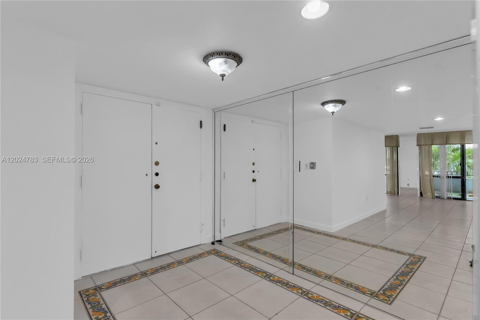 An entryway features white doors, a large mirrored wall, and tiled flooring with decorative borders — 13951 Kendale Lakes Cir # 208A, Miami FL 33183, MIAMI, FL