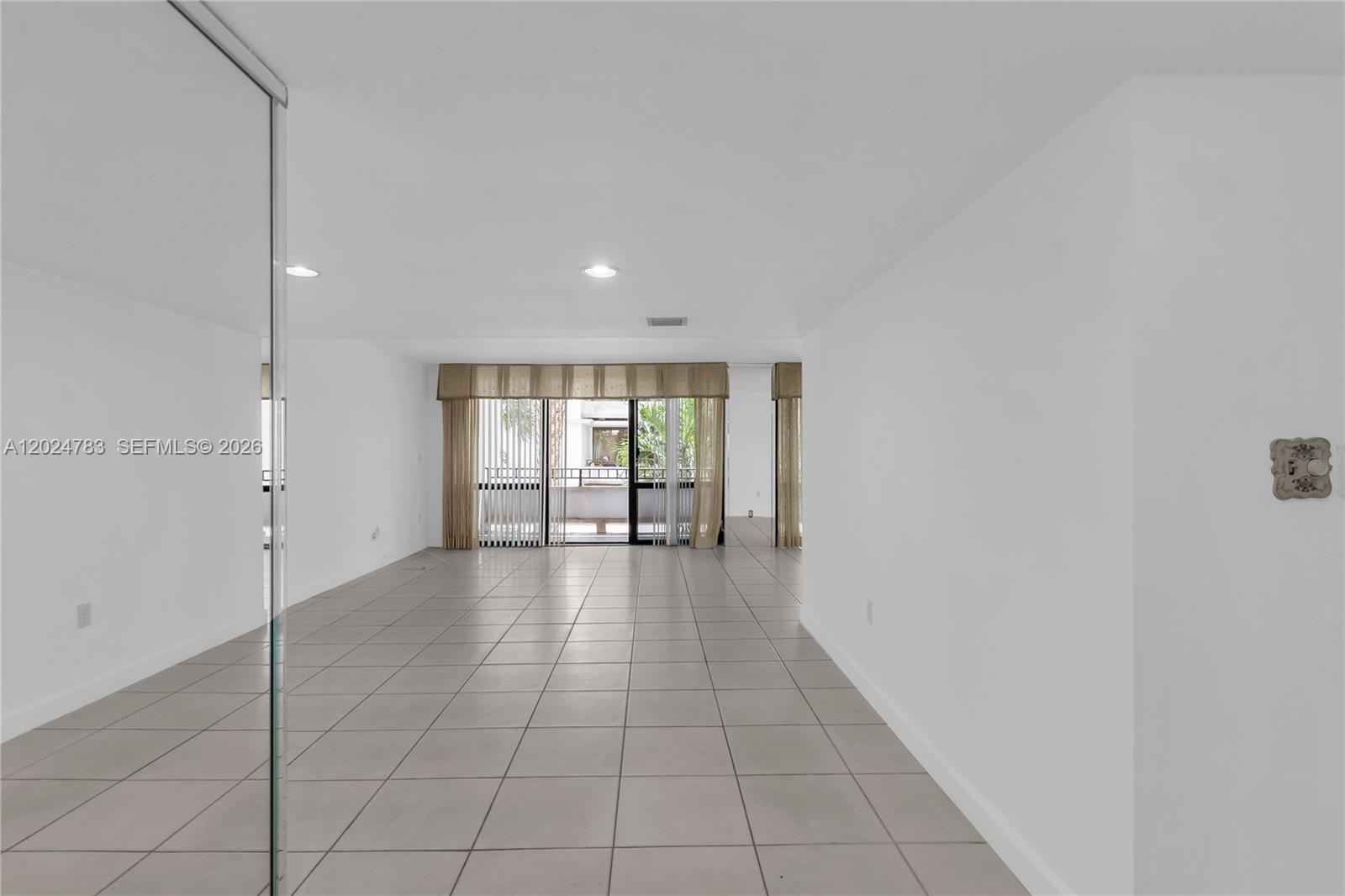 An empty room with white walls, light tile flooring, and a sliding glass balcony door — 13951 Kendale Lakes Cir # 208A, Miami FL 33183, MIAMI, FL