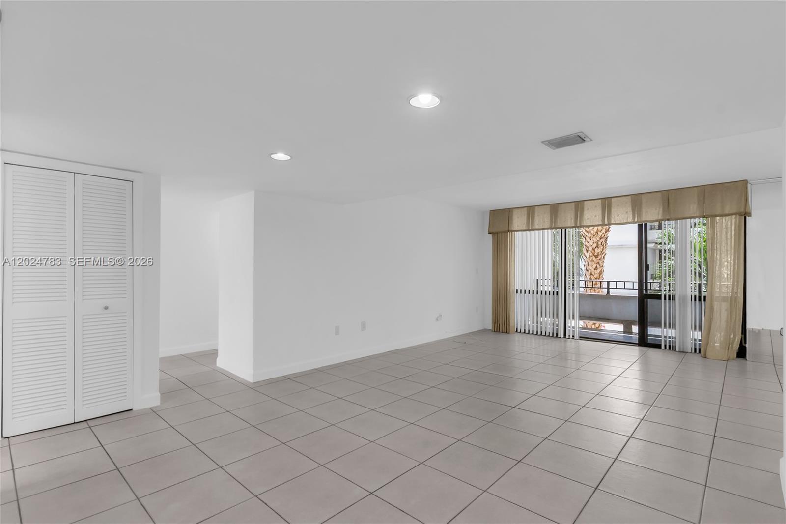 This living room features white walls, light-colored tile flooring, recessed lighting, and a sliding glass door — 13951 Kendale Lakes Cir # 208A, Miami FL 33183, MIAMI, FL