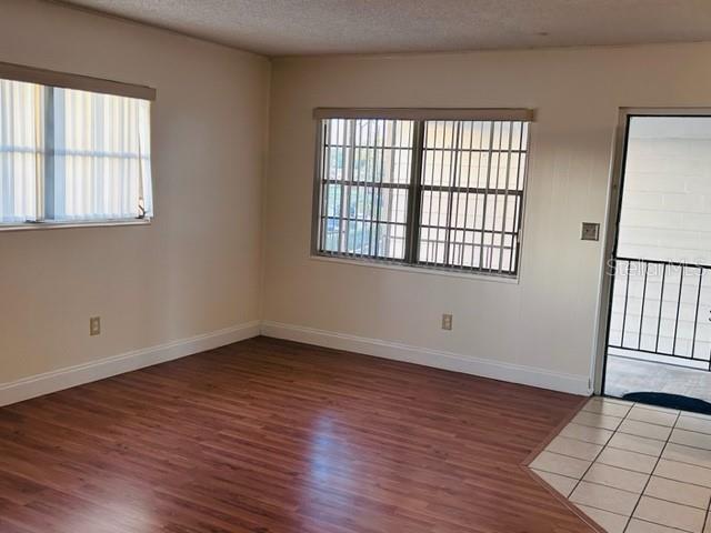 An empty room features wood-look flooring, beige walls, two windows with blinds, and a doorway — 2887 S OSCEOLA AVENUE UNIT D, ORLANDO, FL