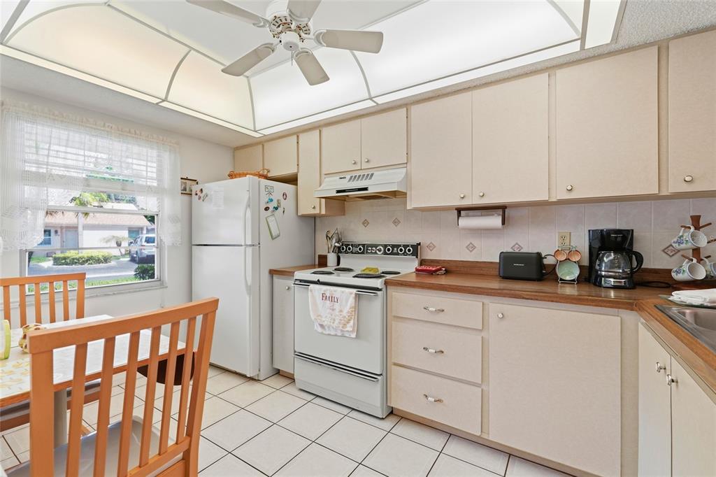A kitchen features white appliances, light-colored cabinets, a wooden countertop, and a ceiling fan — 2609 WOODGATE LANE UNIT K4, SARASOTA, FL