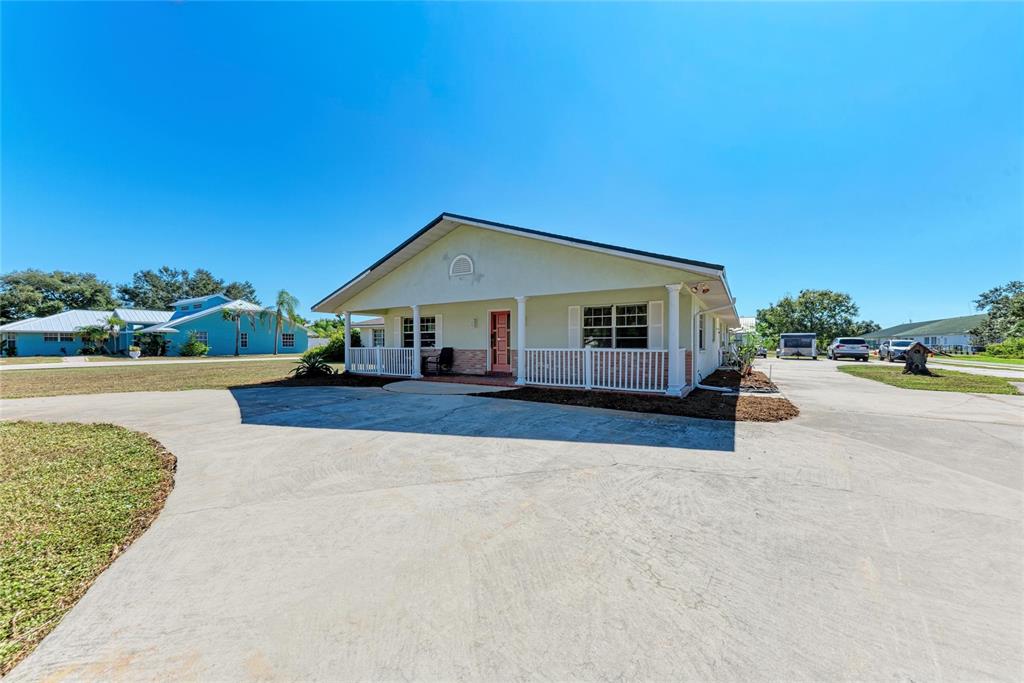 A light green single-story house features a front porch, white railings, and a concrete driveway — 1499 17TH STREET W, PALMETTO, FL