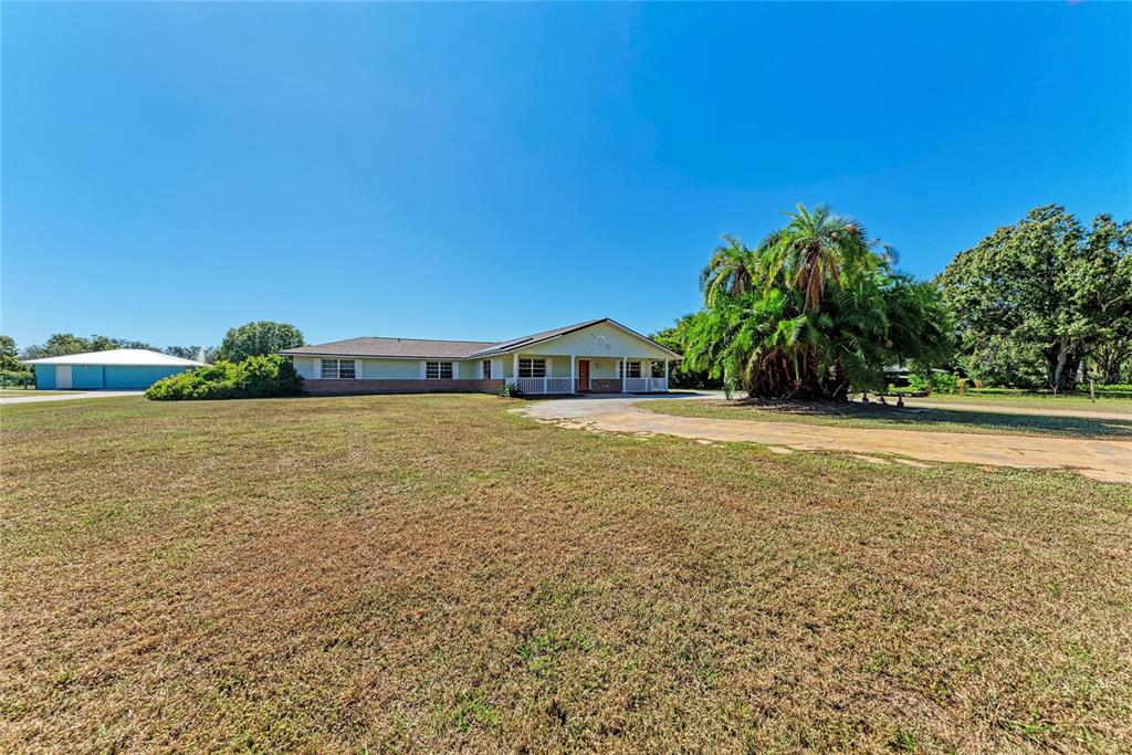 A single-story house with a porch and a large palm tree sits on a lawn — 1499 17TH STREET W, PALMETTO, FL