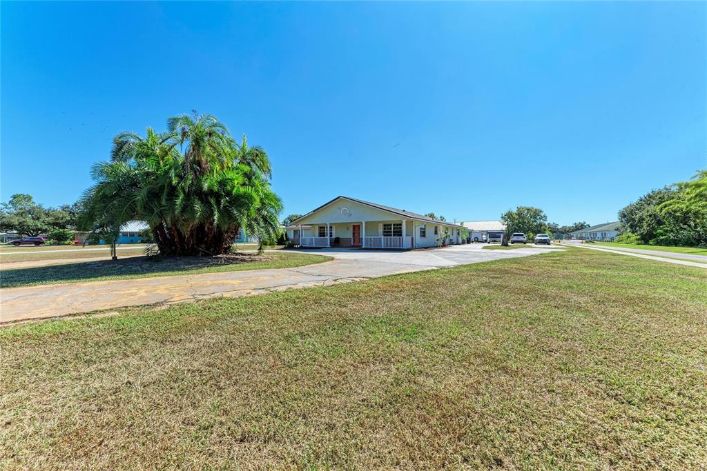 A light-colored house with a front porch sits on a large, grassy lot — 1499 17TH STREET W, PALMETTO, FL