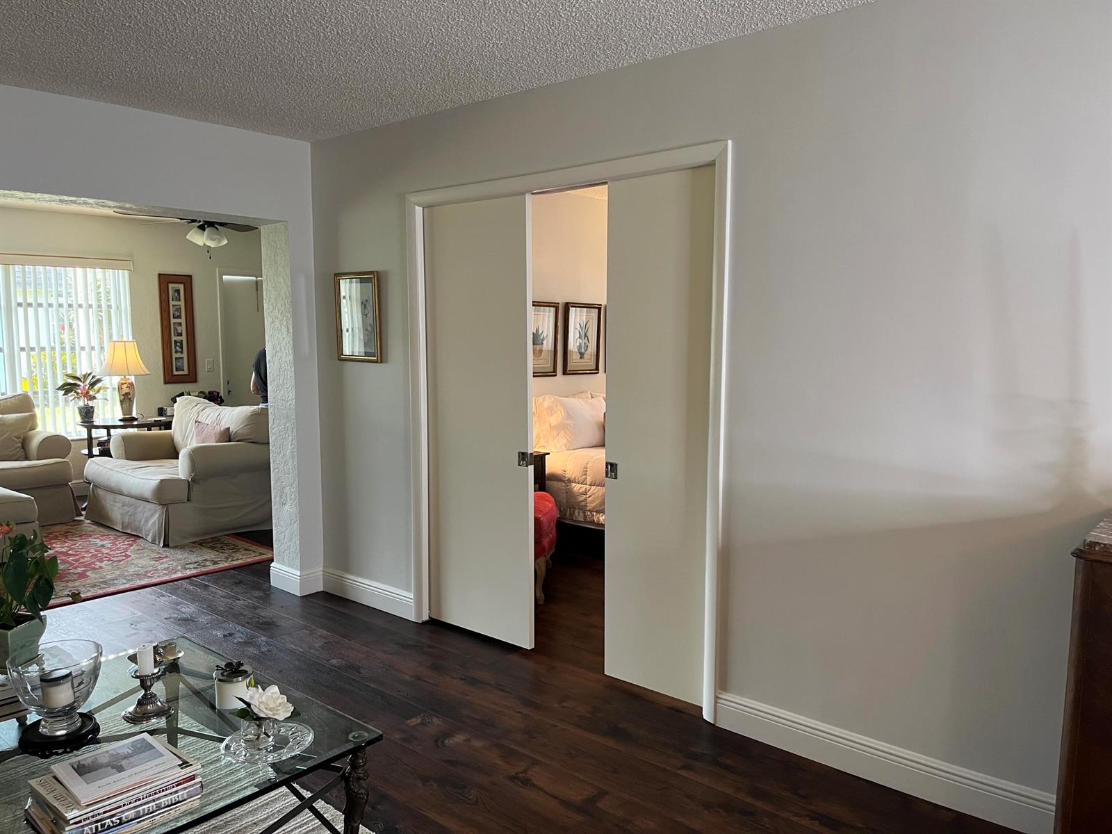A living room with dark wood floors features double sliding doors leading to a bedroom — 2638 Gately Drive E # 112, West Palm Beach FL 33415, WEST PALM BEACH, FL