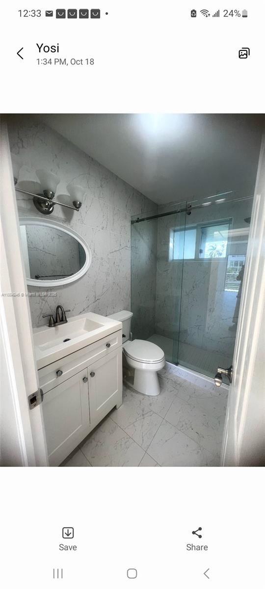 A bathroom features a white vanity, a toilet, and a glass-enclosed shower with marble-patterned tiles — 2300 Park Ln # 211, Hollywood FL 33021, HOLLYWOOD, FL