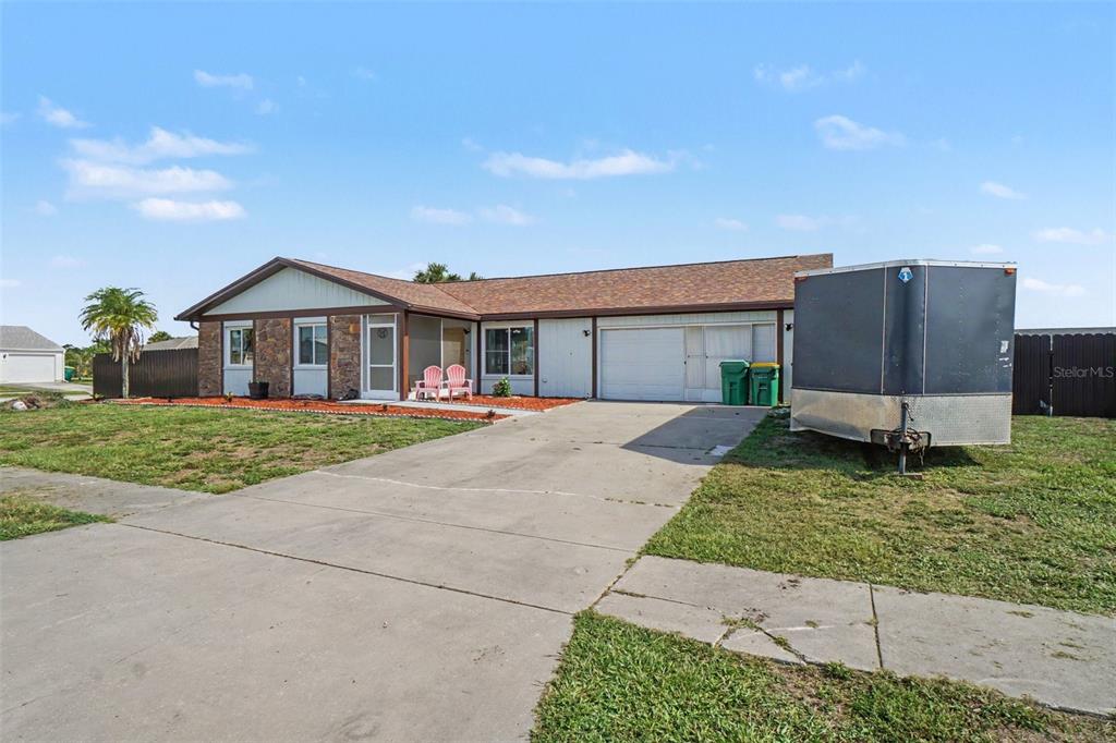 A single-story house with a stone facade, attached garage, and a trailer parked on the driveway — 13238 FOWLER AVE, PORT CHARLOTTE, FL