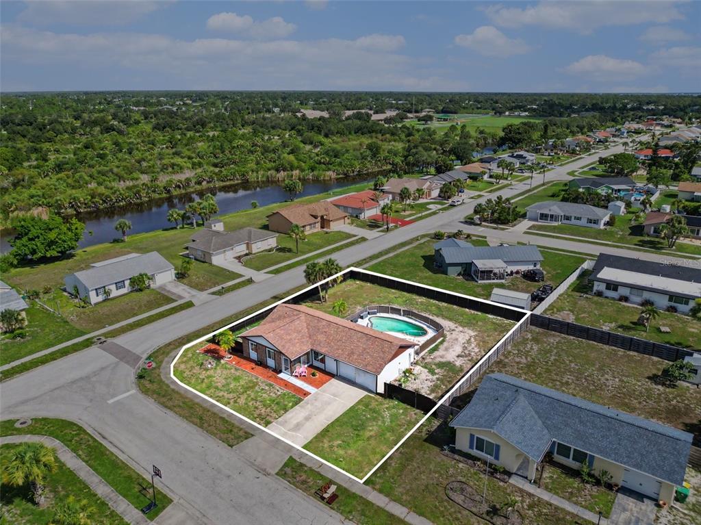 An aerial view shows a single-story house with a swimming pool and fenced backyard — 13238 FOWLER AVE, PORT CHARLOTTE, FL