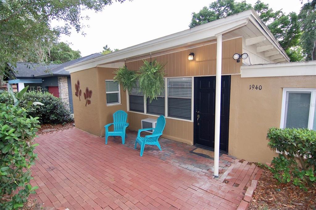 A brick patio sits in front of a tan house with a black door — 1940 SUNSET LANE, CLERMONT, FL