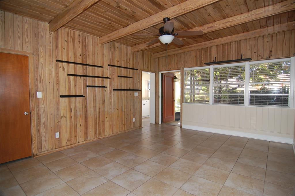 A living room features wood-paneled walls, a beamed ceiling, tile flooring, and large windows — 1940 SUNSET LANE, CLERMONT, FL