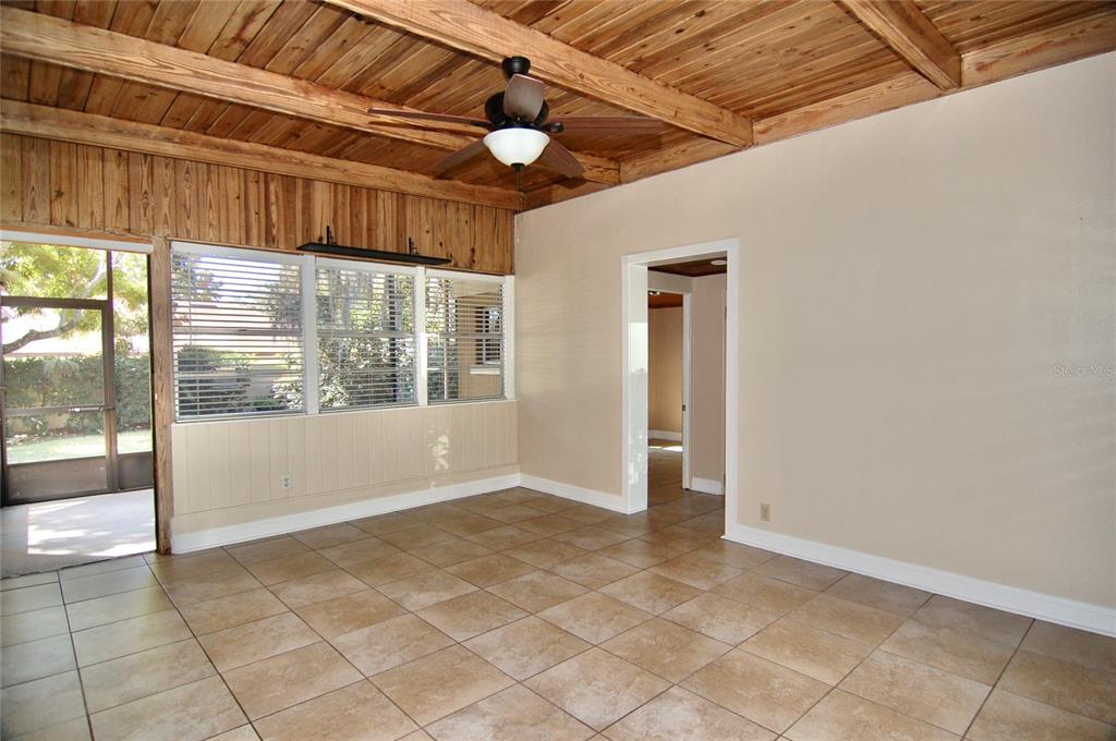 A sunroom with tile flooring, wood-paneled walls, a wood-plank ceiling, and a ceiling fan — 1940 SUNSET LANE, CLERMONT, FL