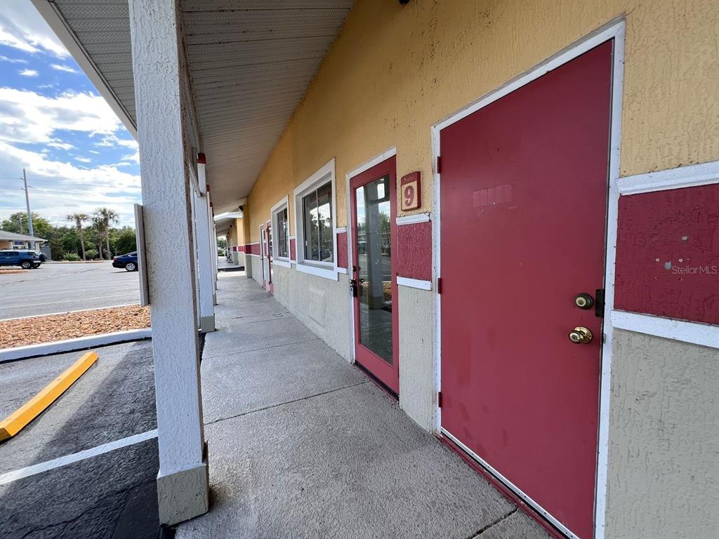 A sidewalk runs along the exterior of a commercial building with red doors and windows — 4400 N HIGHWAY 19A UNIT 9, MOUNT DORA, FL