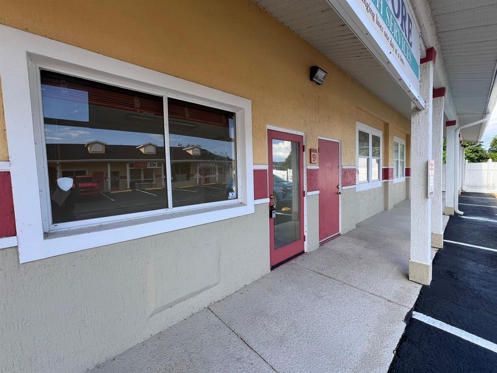 The exterior of a commercial building features a glass door, a red door, and windows — 4400 N HIGHWAY 19A UNIT 9, MOUNT DORA, FL