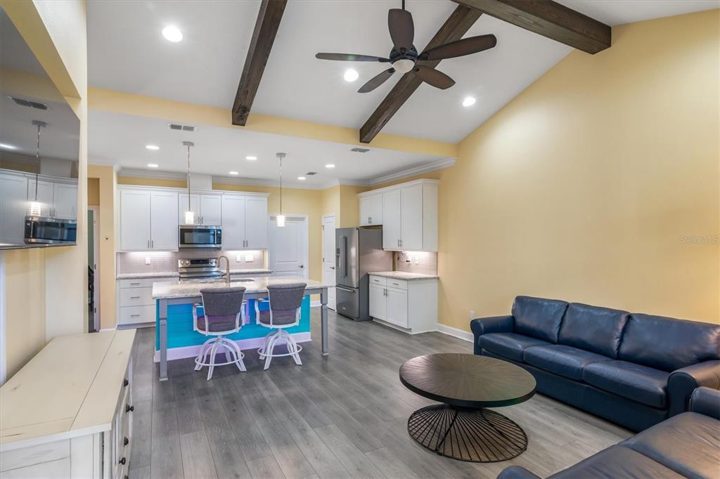 An open-concept kitchen and living area features white cabinetry, a colorful island, and vaulted ceilings — 485 MARGARITAVILLE AVENUE, DAYTONA BEACH, FL