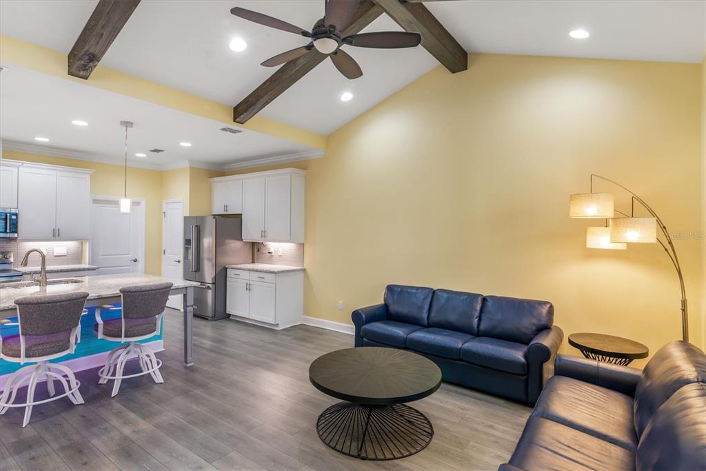 An open-concept kitchen and living area features white cabinets, a blue sofa, and vaulted ceilings — 485 MARGARITAVILLE AVENUE, DAYTONA BEACH, FL