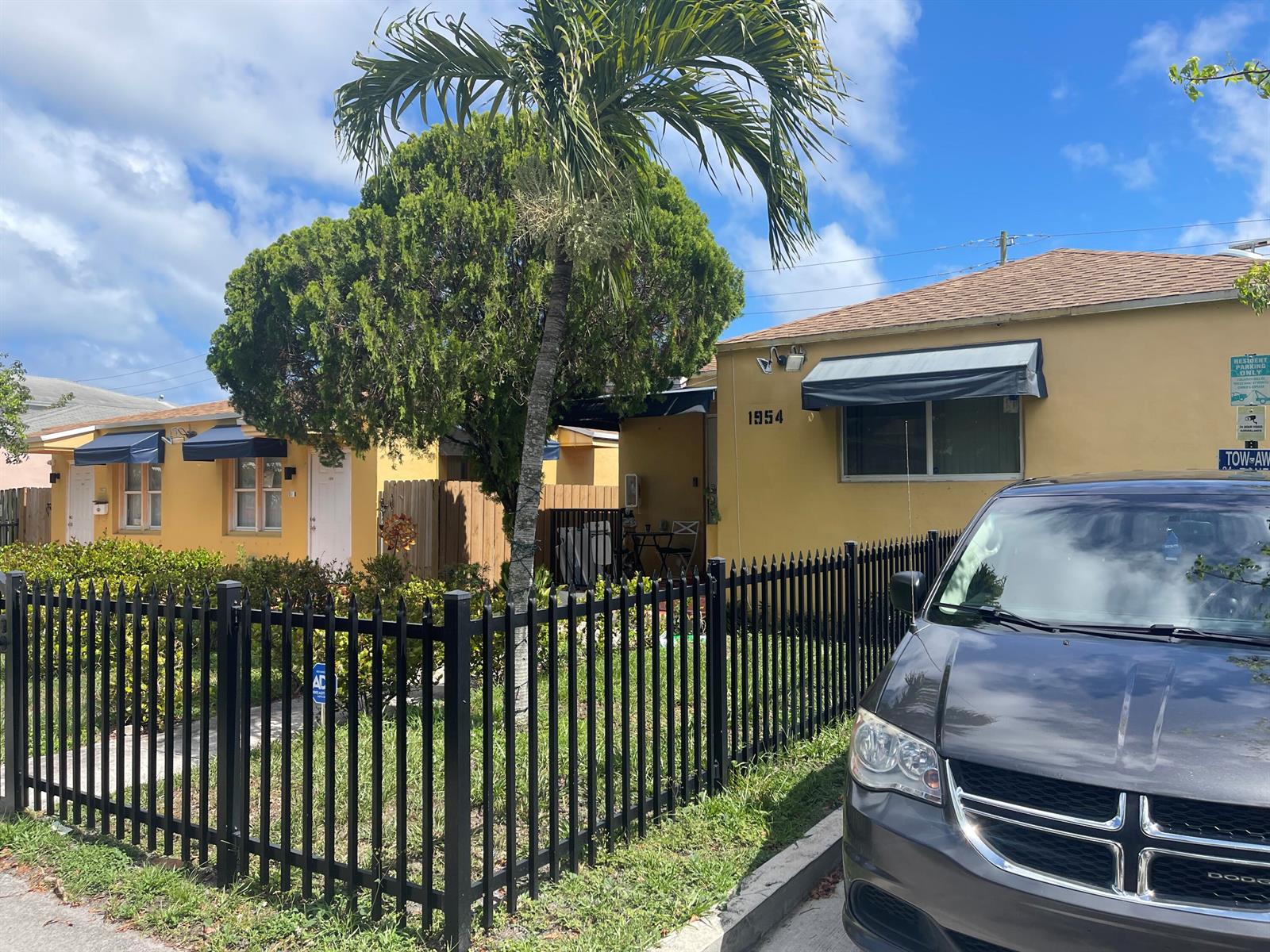 A yellow house with a black metal fence and a palm tree in the front yard — 1948 Buchanan Street, Hollywood FL 33020, HOLLYWOOD, FL