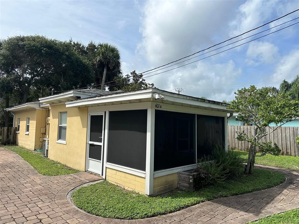 A yellow single-story house features a screened-in porch and a brick paver walkway — 401 OAKWOOD AVENUE UNIT A, NEW SMYRNA BEACH, FL