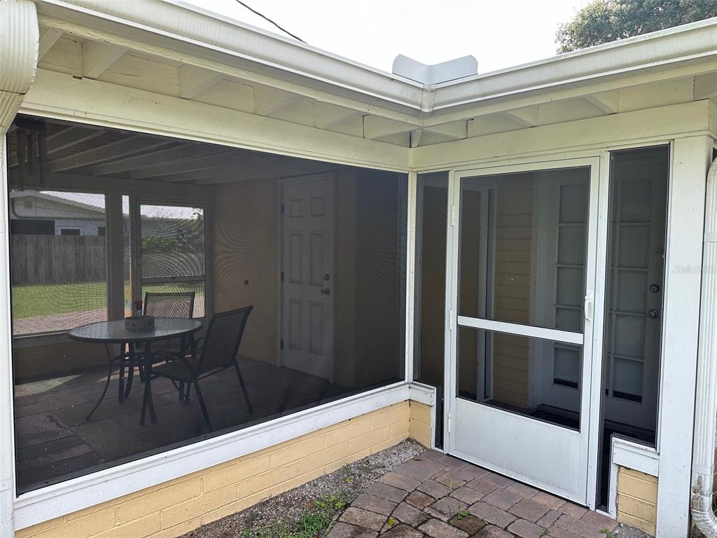 A screened-in patio with a table, chairs, and a white door attached to a house — 401 OAKWOOD AVENUE UNIT A, NEW SMYRNA BEACH, FL