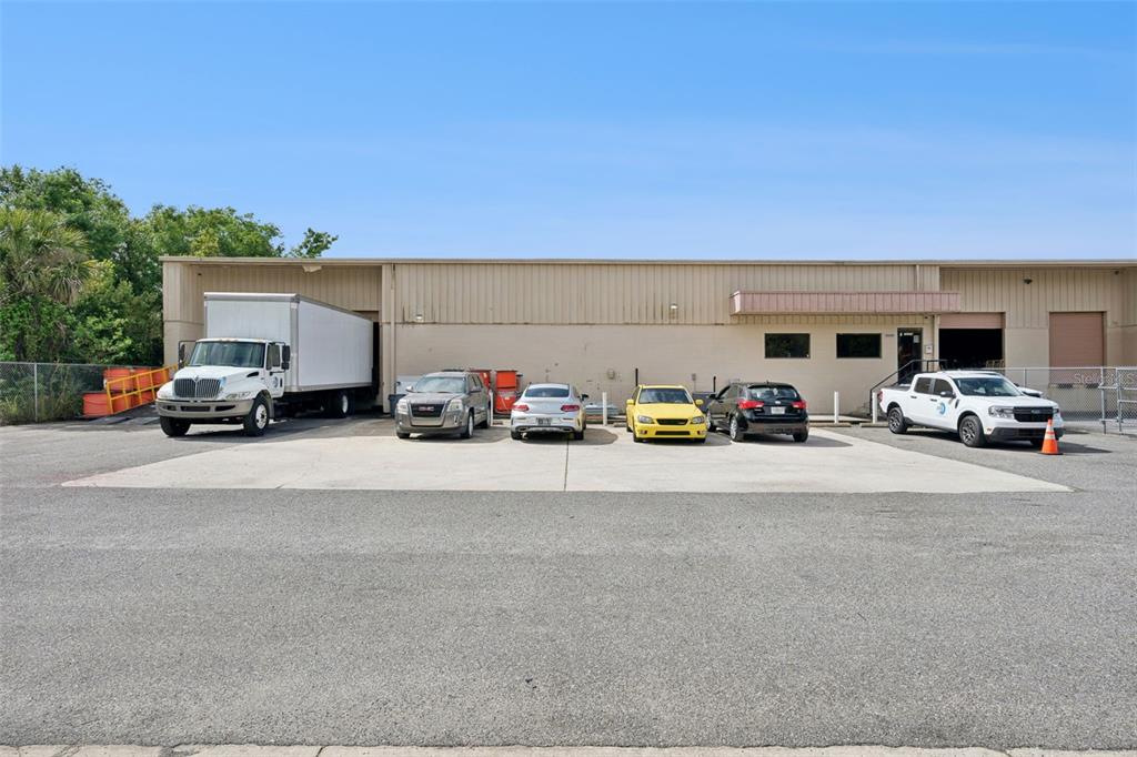 A commercial warehouse building with a loading dock and several parked vehicles in front — 10235 GENERAL DRIVE UNIT 8, ORLANDO, FL