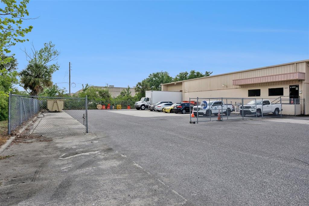 A paved parking lot sits in front of a commercial building with a chain-link fence — 10235 GENERAL DRIVE UNIT 8, ORLANDO, FL