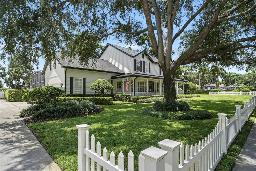 A two-story house with white siding and a front porch sits behind a white fence — 1324 VIC KAY COURT, WINTER GARDEN, FL