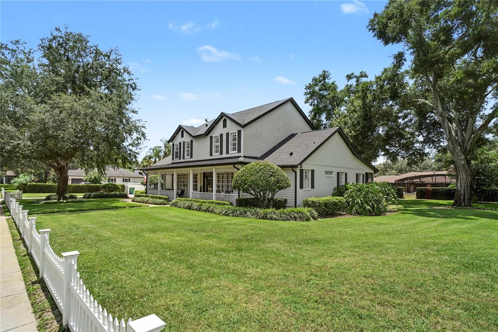 A two-story house with light siding and a wrap-around porch sits on a grassy lawn — 1324 VIC KAY COURT, WINTER GARDEN, FL