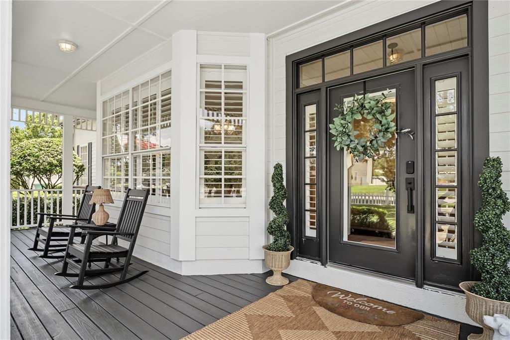 A covered front porch features dark wood decking, two rocking chairs, and a black door — 1324 VIC KAY COURT, WINTER GARDEN, FL