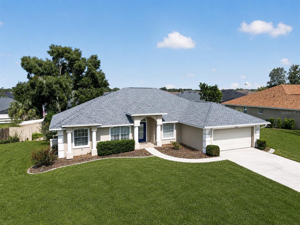 A single-story suburban house with a gray shingled roof, beige stucco walls, and a driveway — 8328 SW 56TH TERRACE, OCALA, FL