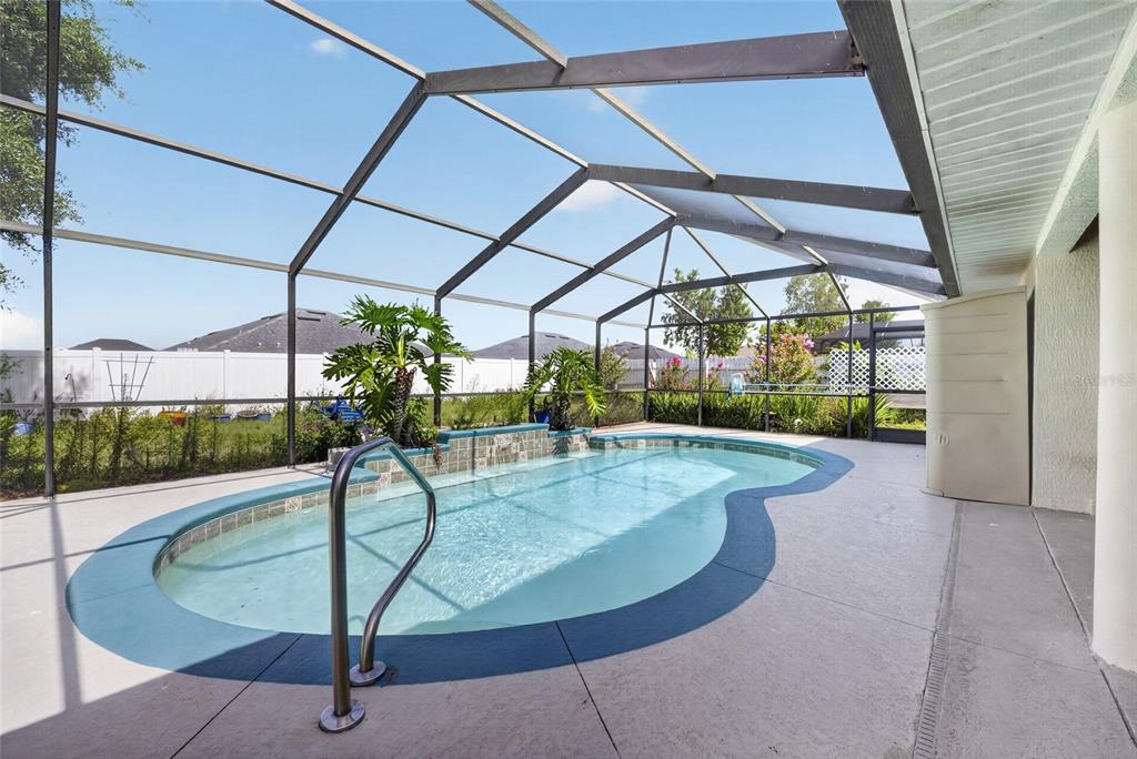 A screened-in swimming pool with a water feature sits on a concrete patio — 8328 SW 56TH TERRACE, OCALA, FL
